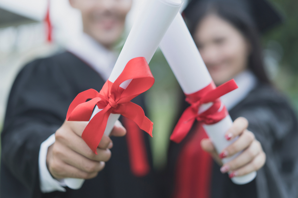 Alunos segurando diplomas de segunda graduação